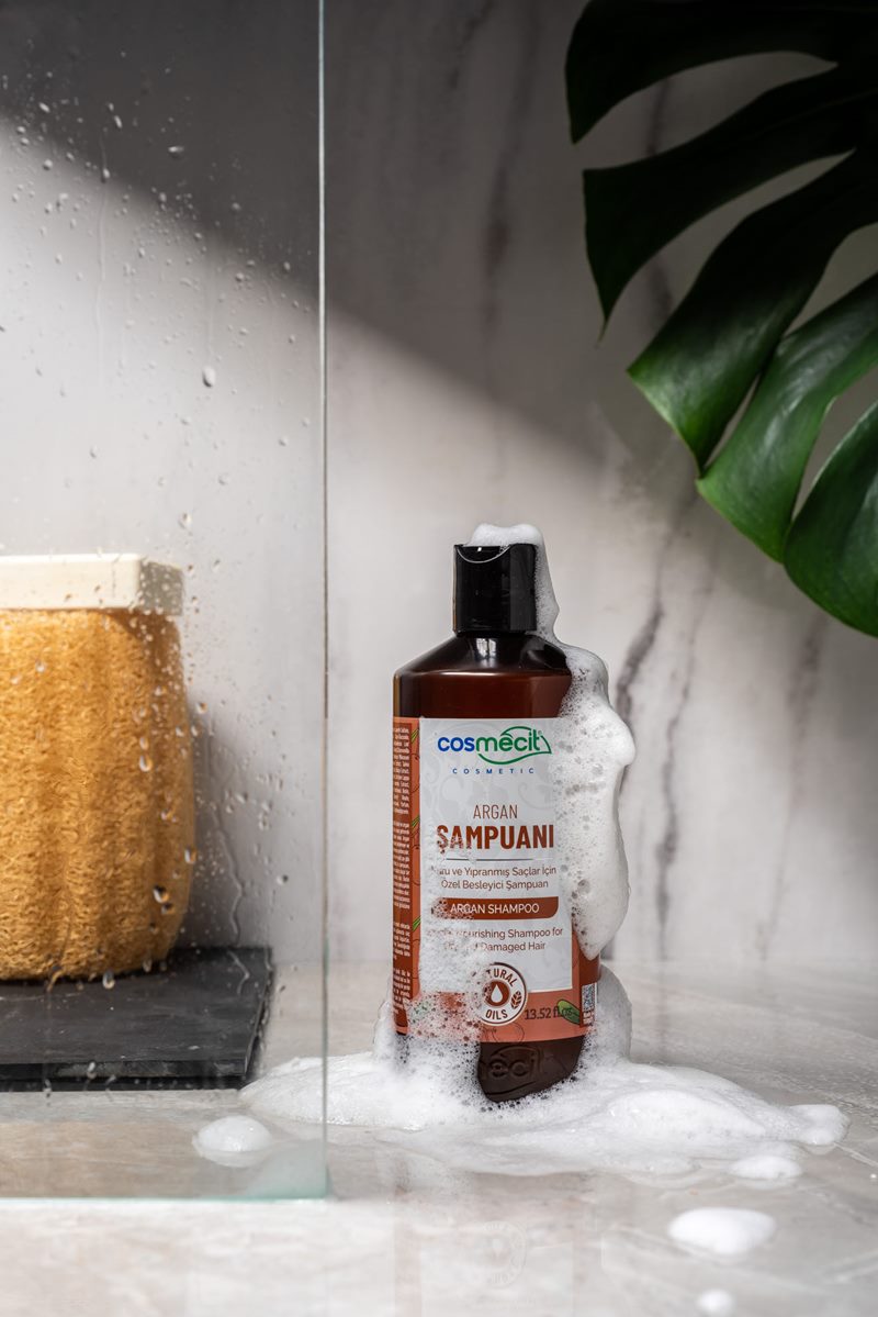 Mecitefendi konsept çekiminde mermer duş zemininde bol köpüklü besleyici argan şampuanı şişesi.