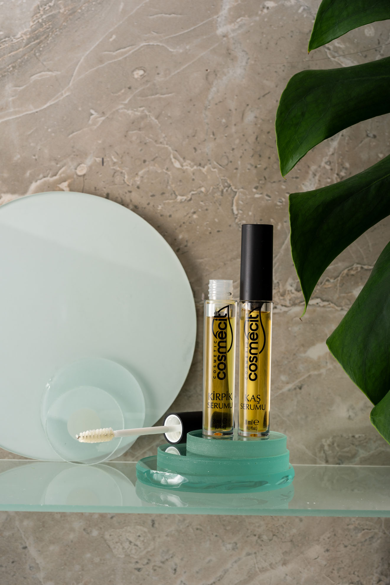 Doğal mermer fonda yeşil stantta duran kaş ve kirpik serumu, İzmir Mecitefendi konsept organik kozmetik çekimini gösteriyor.