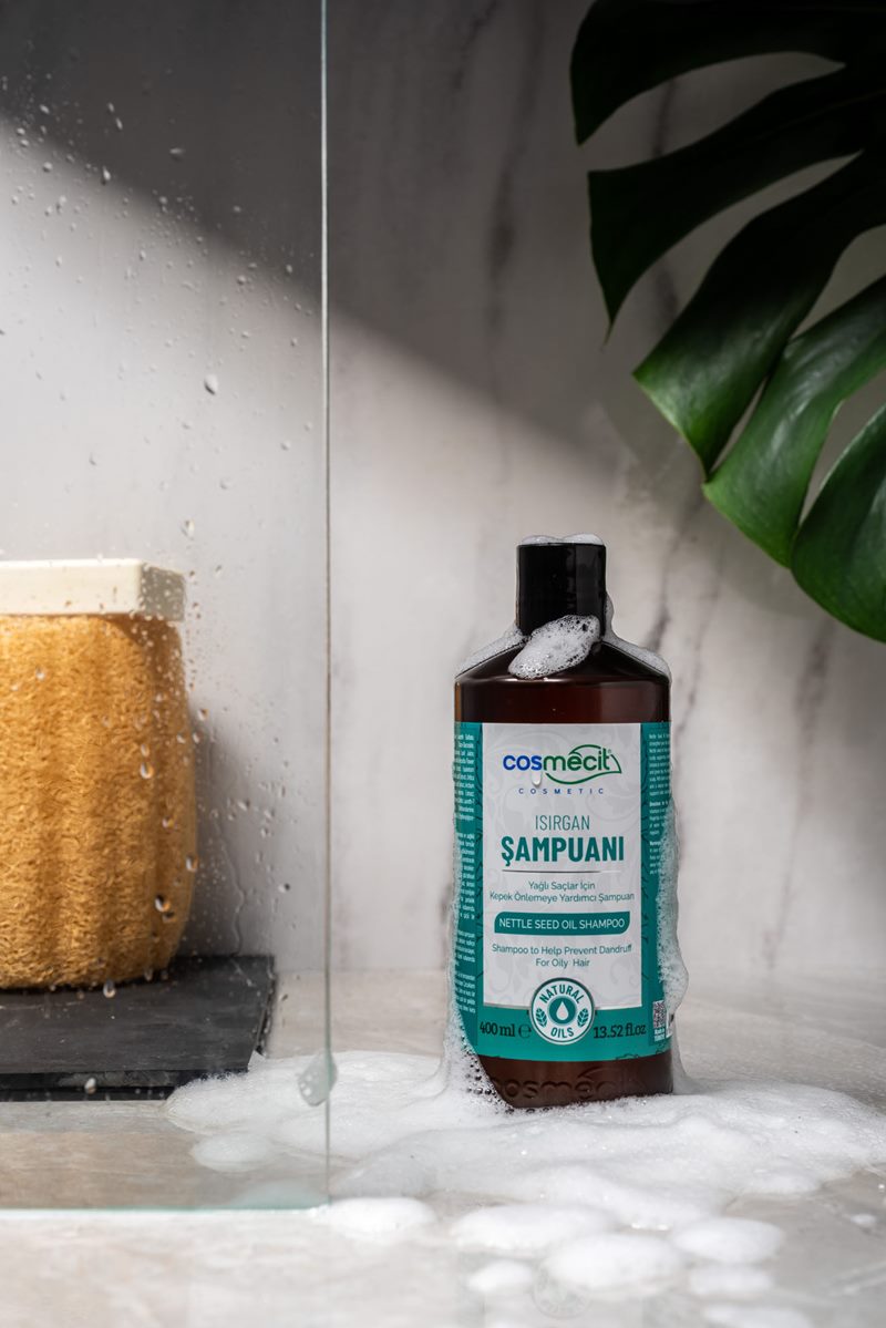 Mecitefendi banyo konsept çekiminde mermer zeminde köpüklü Cosmecit ısırgan şampuanı ve lif.