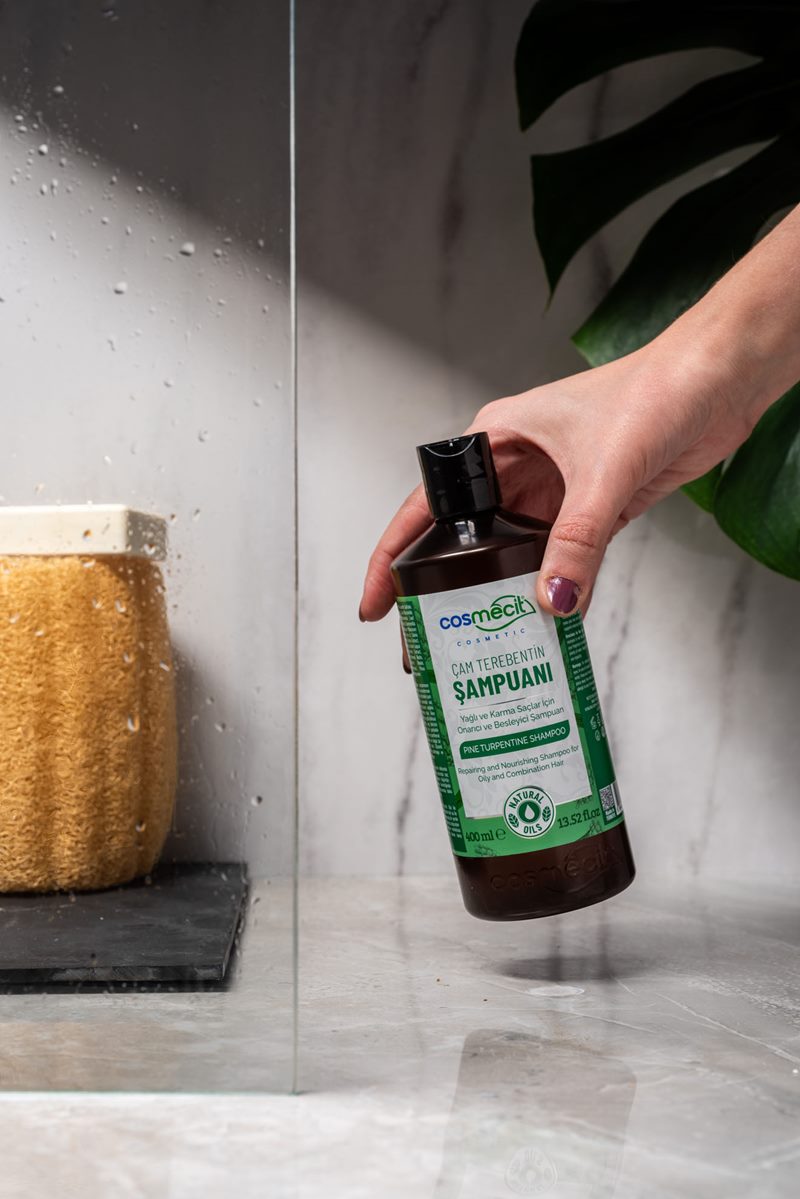 Mecitefendi konsept banyo çekiminde kadın elinde tutulan Cosmecit çam terebentin şampuanı şişesi.