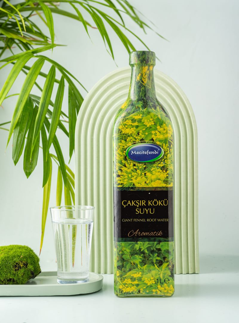 Mecitefendi konsept stüdyo çekiminde yeşil kemer önünde doğal aromatik çakşir kökü suyu şişesi.