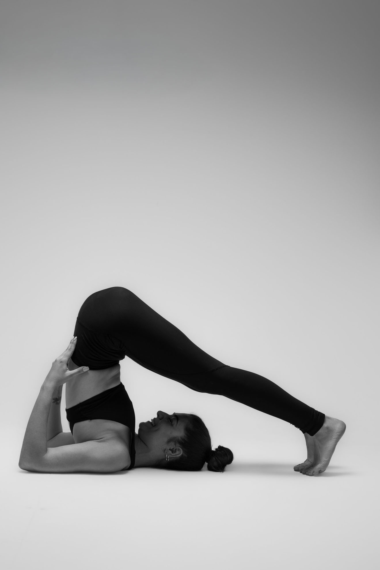 İzmir'deki stüdyoda siyah beyaz çekilen karede, yogawithmelis siyah spor kıyafetiyle klasik bir yoga asana duruşu sergiliyor.
