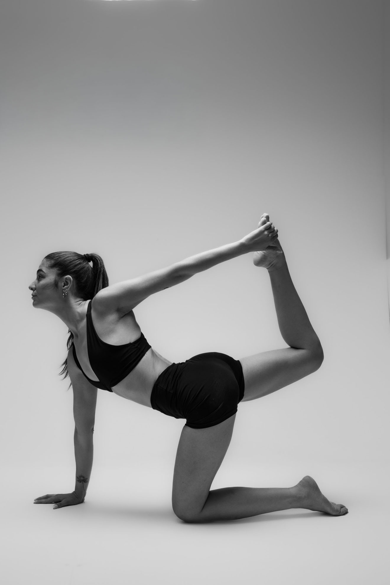 İzmir'deki stüdyoda gri fon önünde siyah beyaz asana duruşu yapan yogawithmelis, estetik ve güçlü bir yoga pozu sergiliyor.
