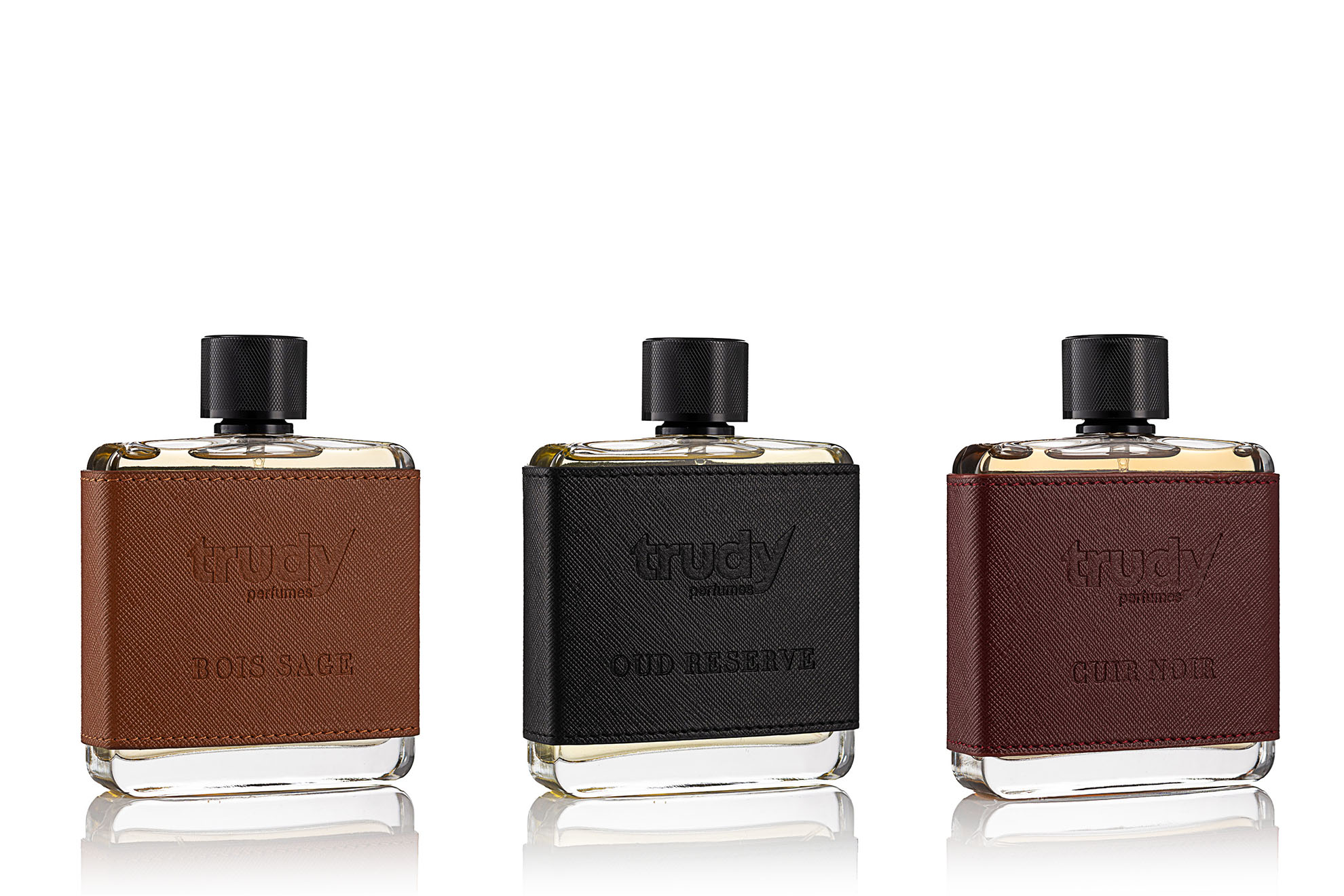 Dikişli deri kaplamalı Trudy Bois Sage, Oud Reserve ve Cuir Noir şişelerinin beyaz fonda çekilen parfüm ürün fotoğrafı.