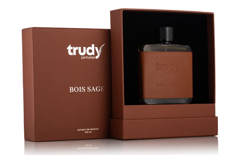 Kahverengi hediye kutusu ve taba deri kılıflı şişesiyle Trudy Bois Sage modelinin beyaz fonda çekilen parfüm ürün fotoğrafı.
