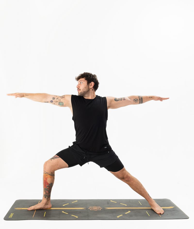 İzmir stüdyo zemininde erkek yoga eğitmeninin güçlü savaşçı iki duruşunu sunduğu Kentli Gurular yoga fotoğraf çekimi.