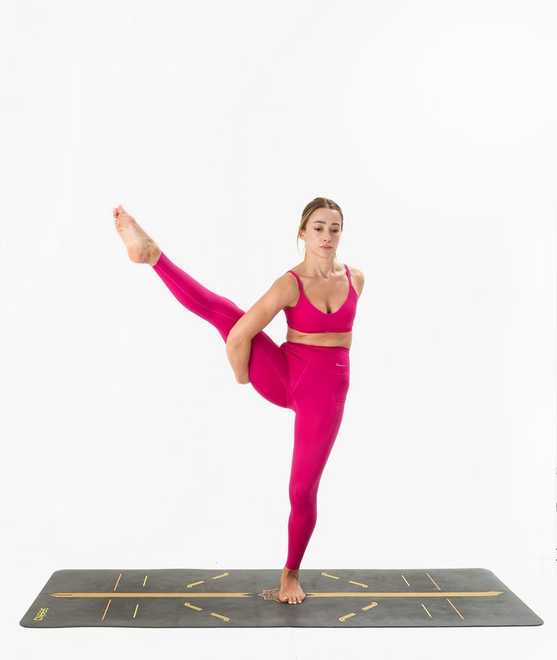 İzmir stüdyoda kadın yoga eğitmeninin tek ayak üstünde, diğer bacağını yukarı kaldırarak denge kurduğu Kentli Gurular yoga fotoğraf çekimi.