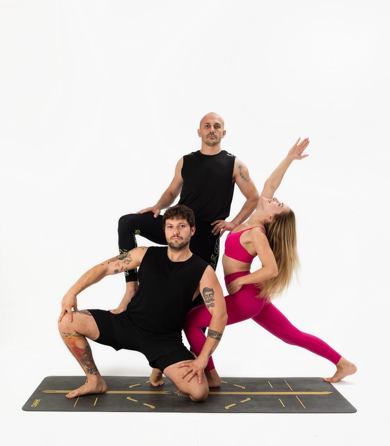 İzmir stüdyo fonunda üç yoga eğitmeninin kademeli grup piramidi sergilediği Kentli Gurular yoga fotoğraf çekimi.