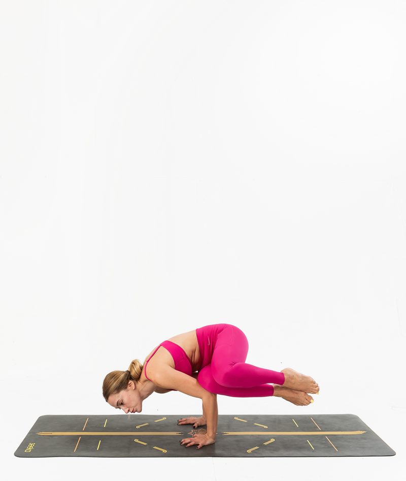 İzmir stüdyo zemininde kadın yoga eğitmeninin yan karga kol dengesinde durduğu Kentli Gurular yoga fotoğraf çekimi.
