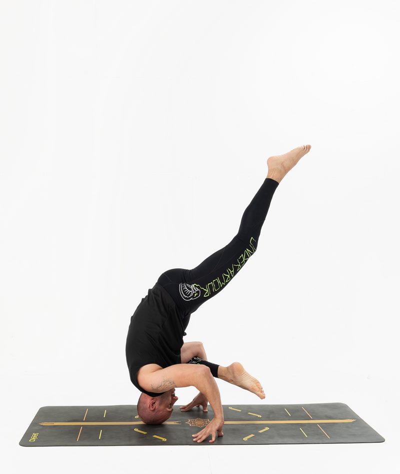 İzmir stüdyoda erkek eğitmenin üçayak baş duruşunda tek bacağını kaldırdığı Kentli Gurular yoga fotoğraf çekimi.