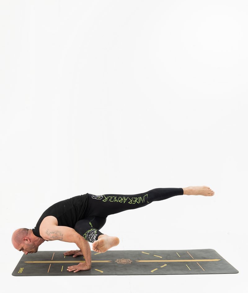 İzmir stüdyoda erkek eğitmenin uçan güvercin kol dengesinde bacağını uzattığı Kentli Gurular yoga fotoğraf çekimi.