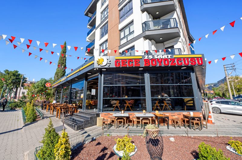 24 Saat Gece Boyozcusu dış cephesi, camlı salon, terası ve bayraklarıyla İzmir'de restoran mimari fotoğraf çekimi.