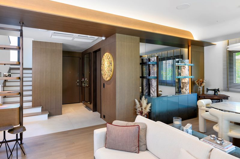 Villada salondan girişe ve merdivene geçiş: ahşap kaplı kolon, mavi vitrin ünitesi ve gizli aydınlatmalı tavan.