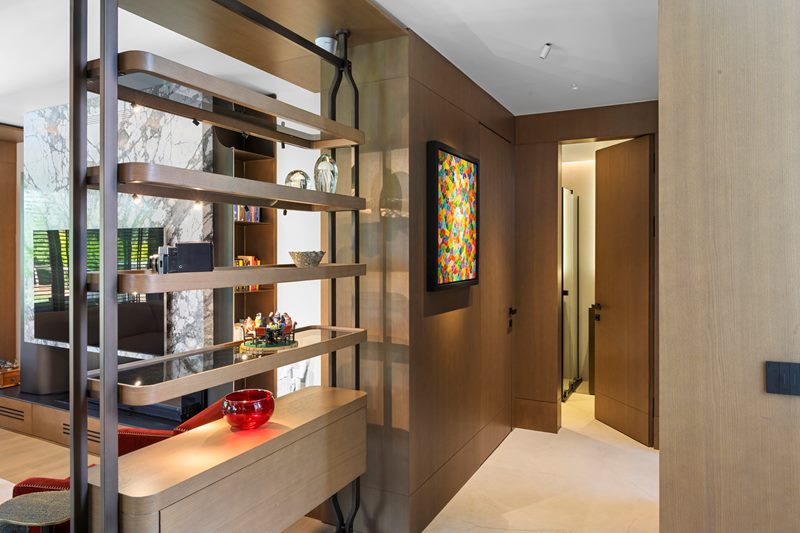 Villa koridorunda metal ve ahşap açık raf, duvara gömülü aydınlatmalı niş ve boydan boya ahşap duvar kaplaması.