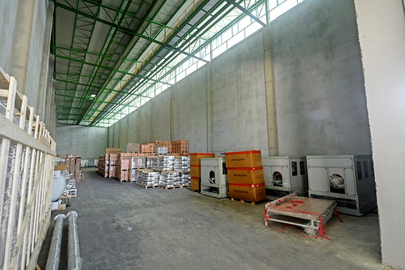 HYT Lojistik antreposunda ahşap sandıklar, paletli yükler ve makineler, yüksek beton duvarlar arasında geniş açı.