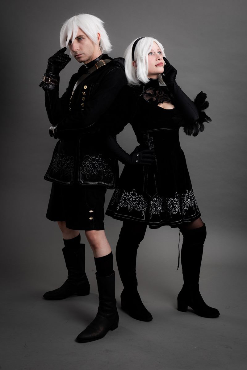 Gri kağıt fon önünde sırt sırta tam boy poz veren NieR Automata 2B ve 9S ikilisi İzmir cosplay fotoğraf çekimi.