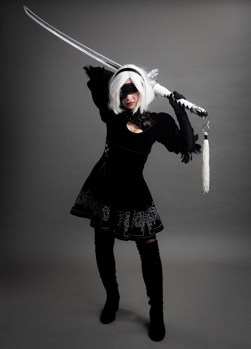 İzmir cosplay fotoğraf çekimi stüdyosunda siyah göz bandı ve omzundaki uzun kılıcıyla tam boy poz veren 2B modeli.