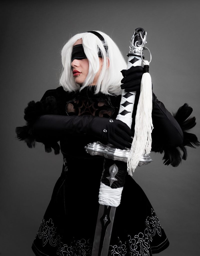 İzmir cosplay fotoğraf çekimi kapsamında gri fonda el yapımı kılıcının kabzasını tutan 2B karakteri orta plan portresi.